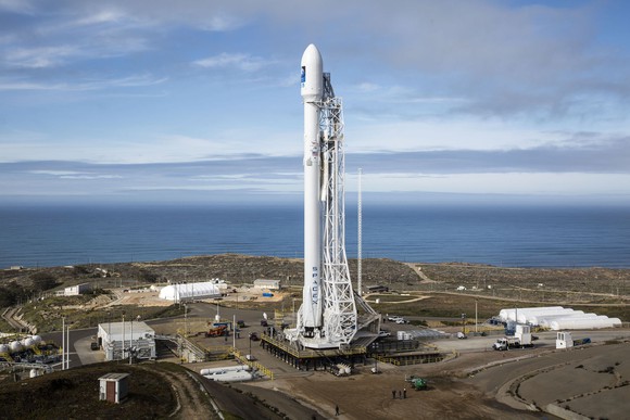 Falcon 9 rocket sitting on launchpad with partly cloudy skies