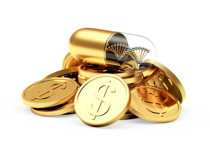 A gold pill rests atop a pile of gold coins
