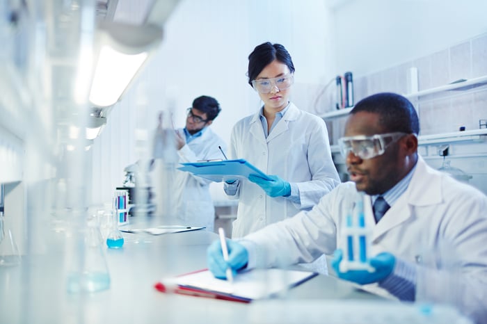 Lab scientists of different ethnicities work together at a work station.