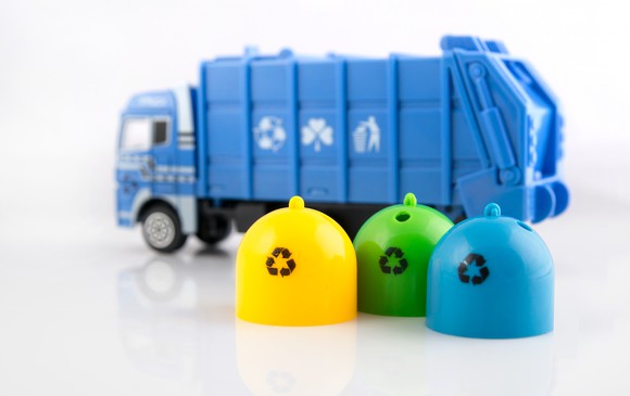 Blue toy garbage truck with three toy recycling bins alongside it