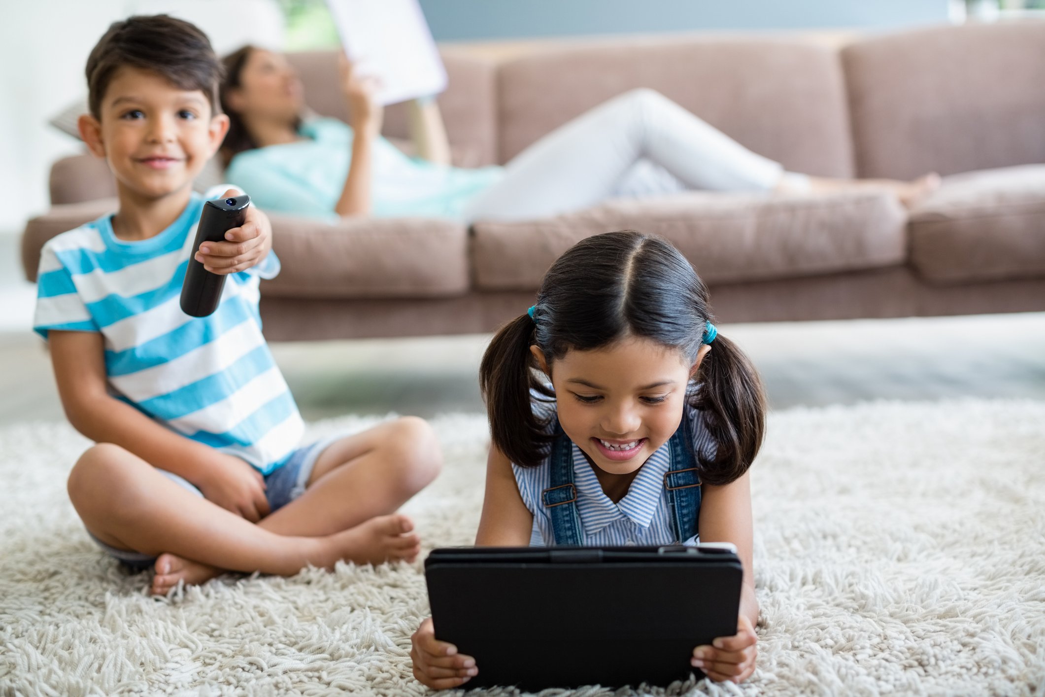 Boy watching TV and girl using tablet in the living room