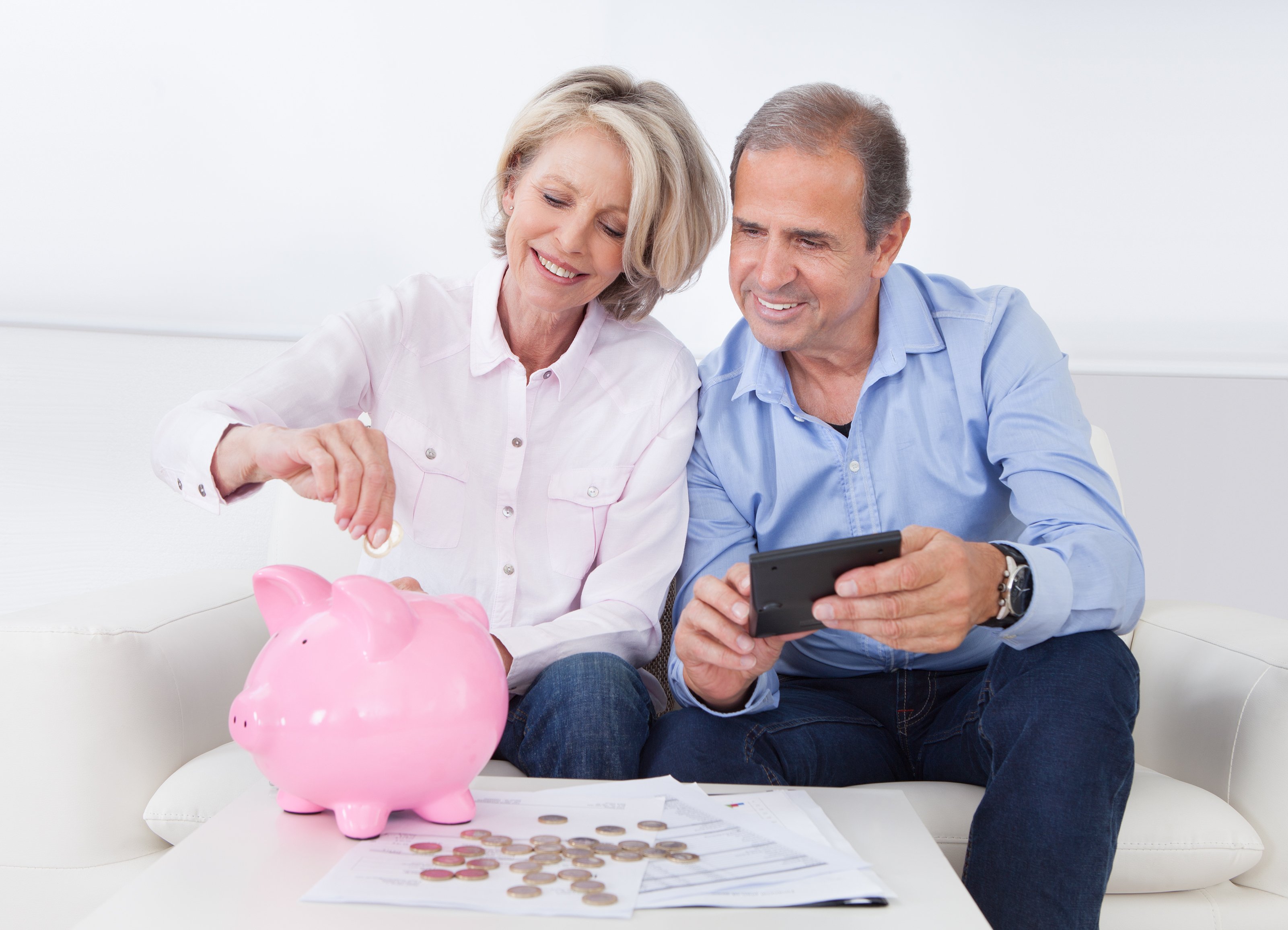 An elderly couple putting money in the piggy bank.