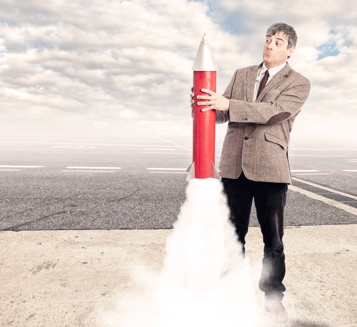 Man holding onto a toy rocket that's about to lift off. 