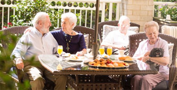 Four seniors sit around a breakfast table.
