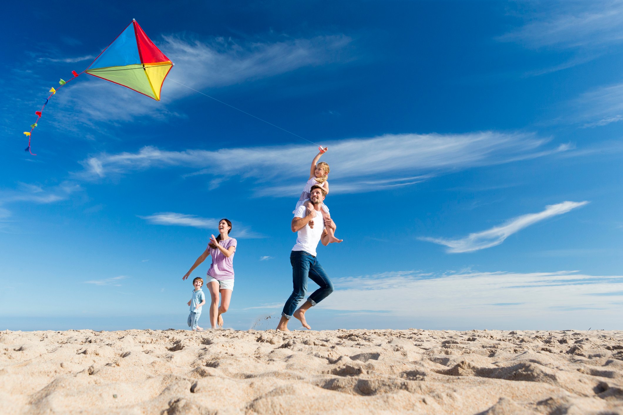 A family flies a kite on a beach.