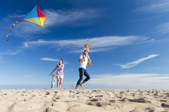 A family flies a kite on a beach.