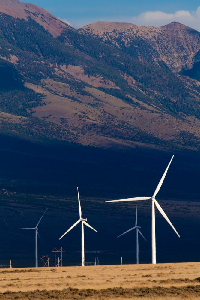 Several wind turbines in front of mountains.
