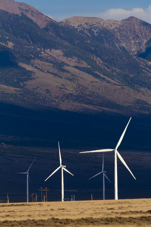 Several wind turbines in front of mountains.