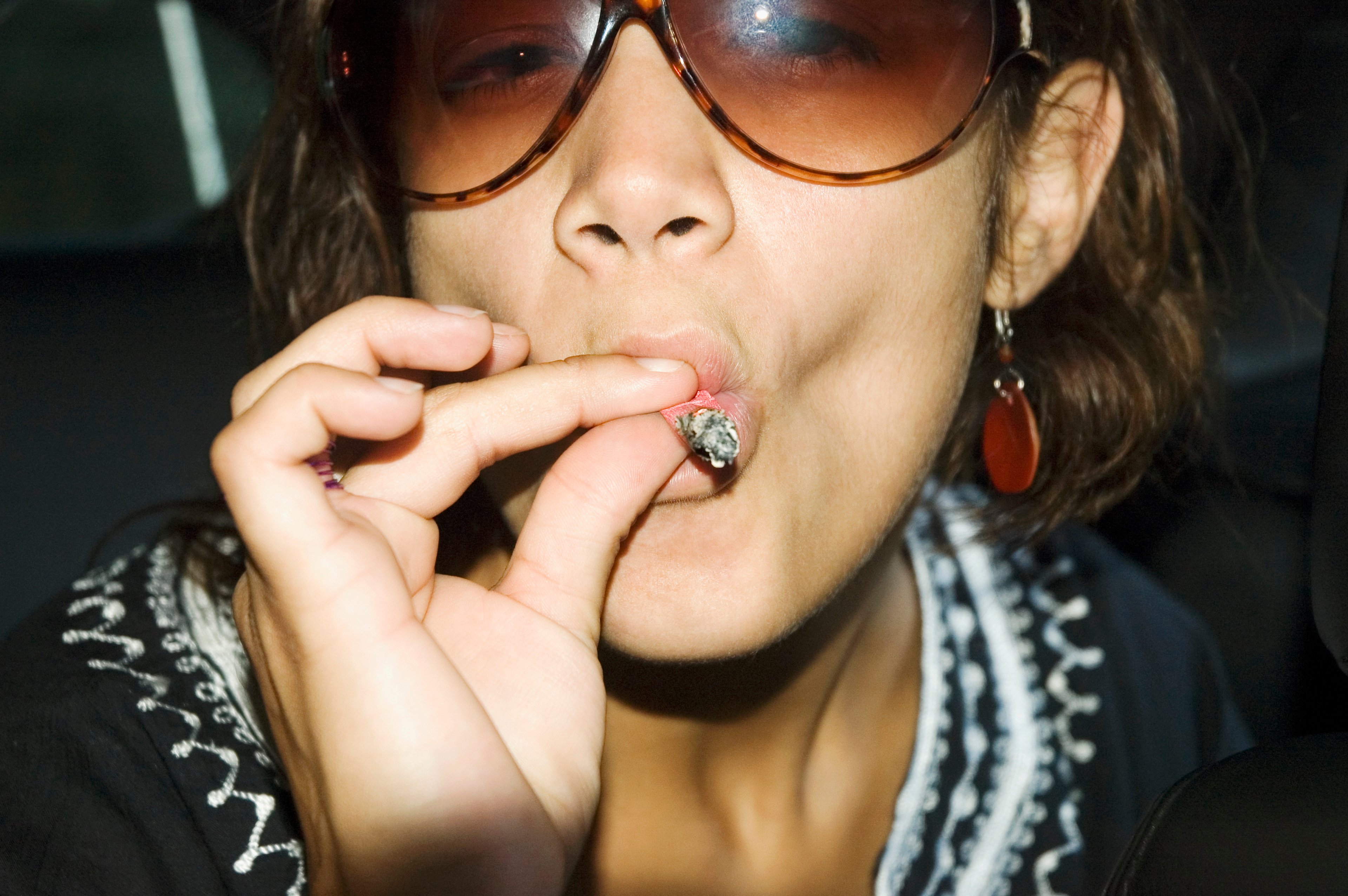 A young woman takes a drag from a marijuana joint.