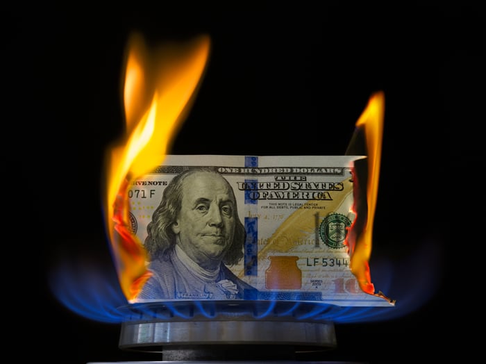 Hundred dollar bill going up in flames on stove top burner. 