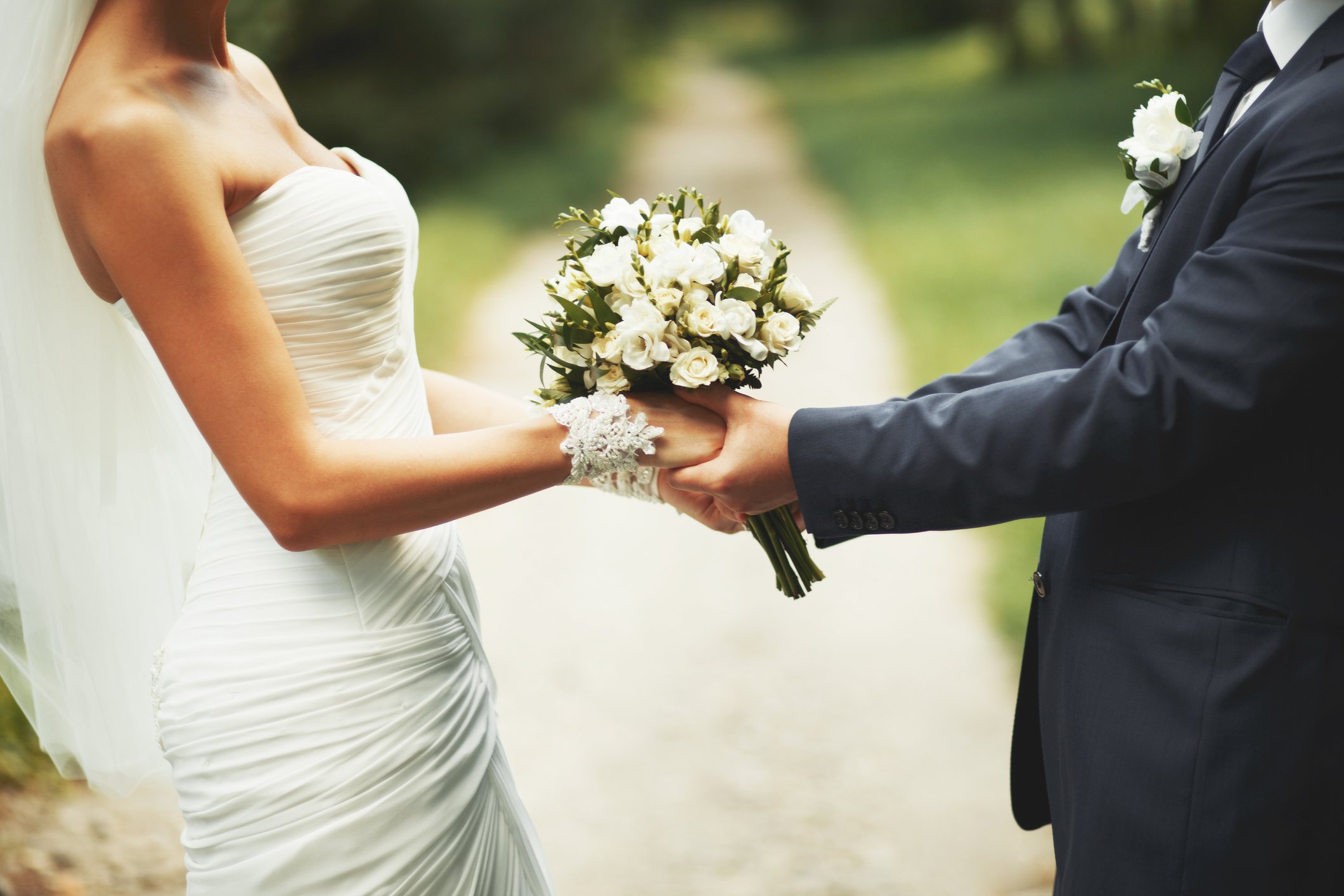 A bride and groom hold a wedding bouquet