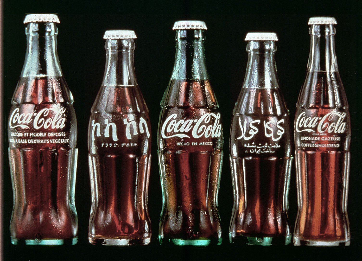 Coca-Cola bottles from around the world with labels in different languages. 