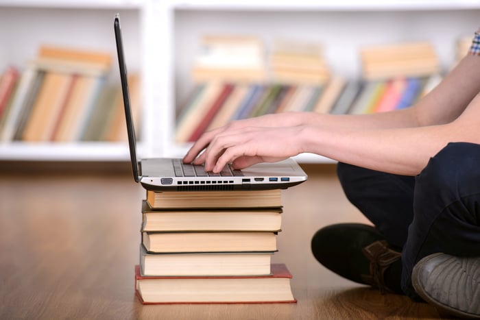 Student using books as a stand for a computer