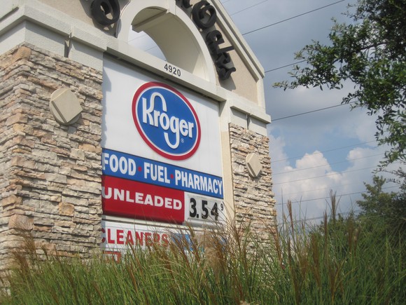 A Kroger sign behind grass showing gas prices