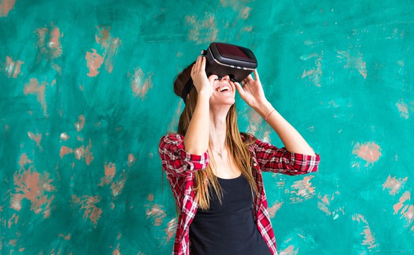 Picture of a woman next to a wall wearing a virtual reality headset.