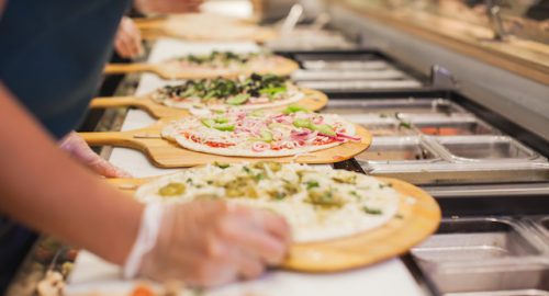 Pizza being made in an assembly line fashion