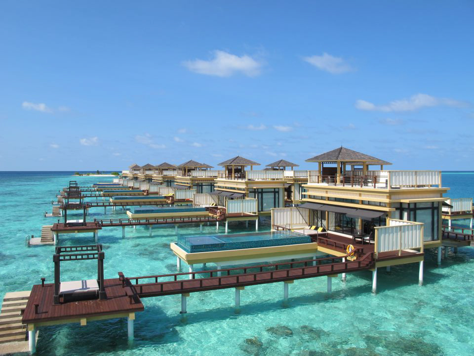 A set of bungalows on a dock over a turquoise-colored sea