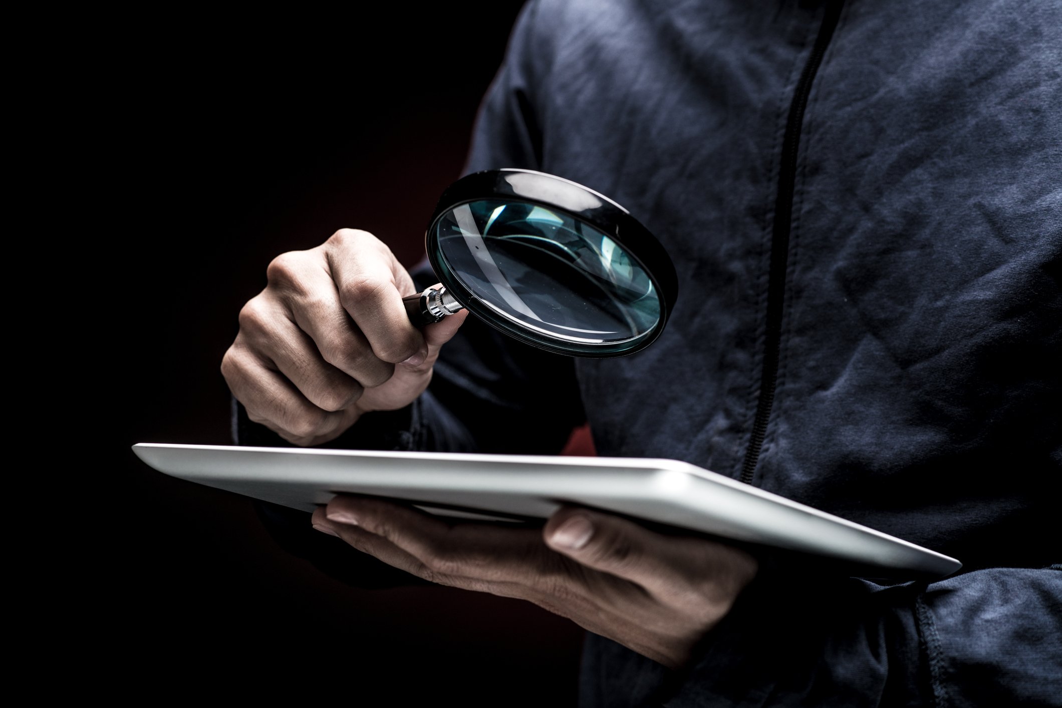 A detective looking at a document with a magnifying glass.