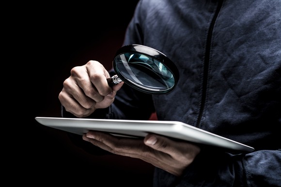 A detective looking at a document with a magnifying glass.