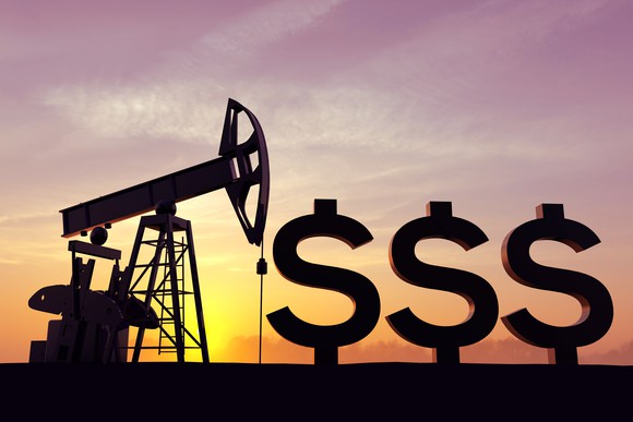 An onshore oil rig operating on a field next to three large dollar signs.