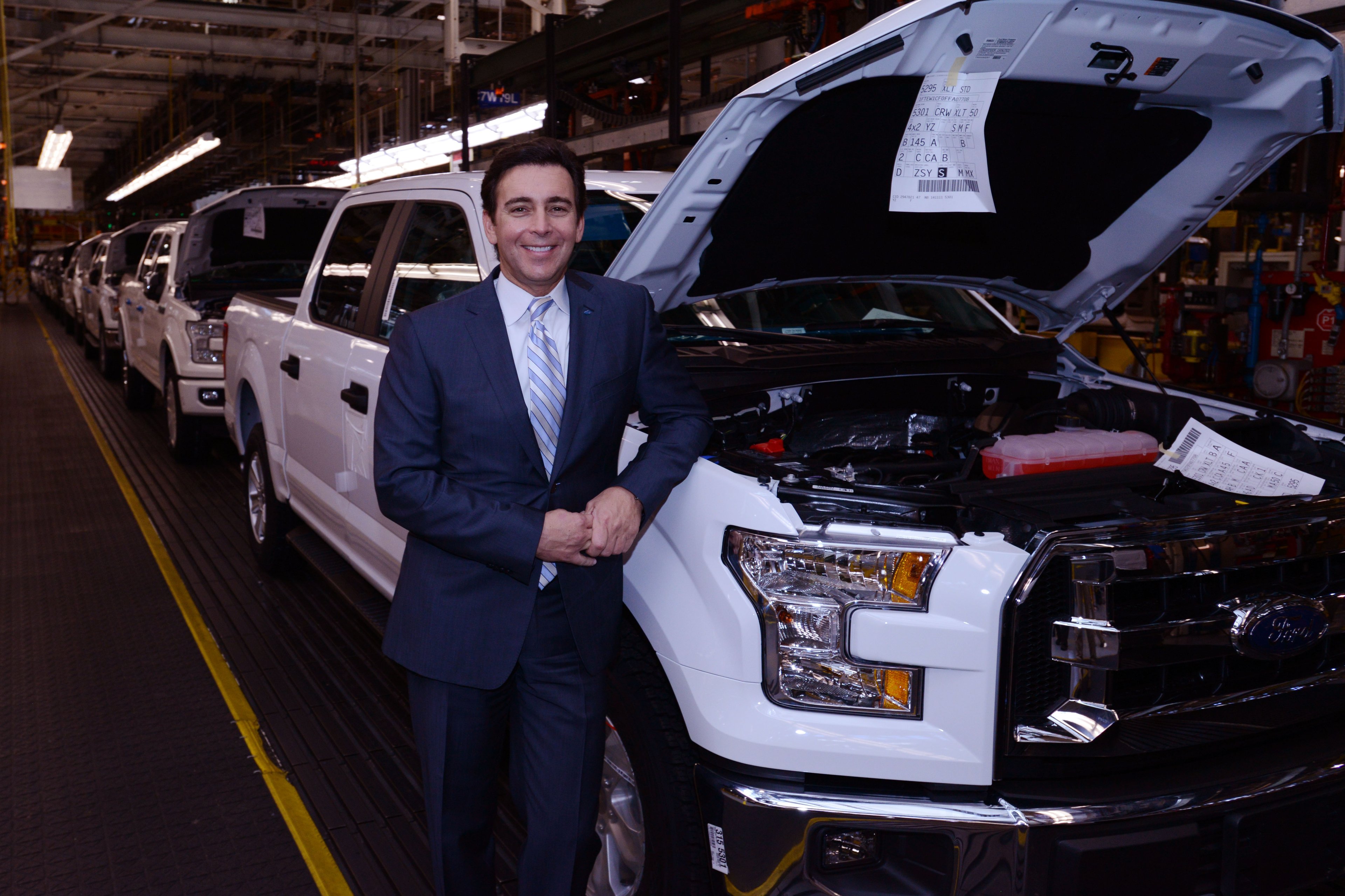 Mark Fields with a white F-150 pickup on an assembly line. 
