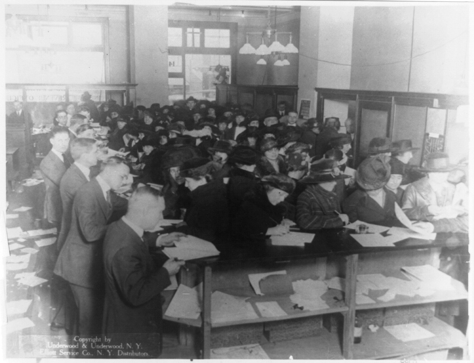 People filing taxes in an office in 1920.
