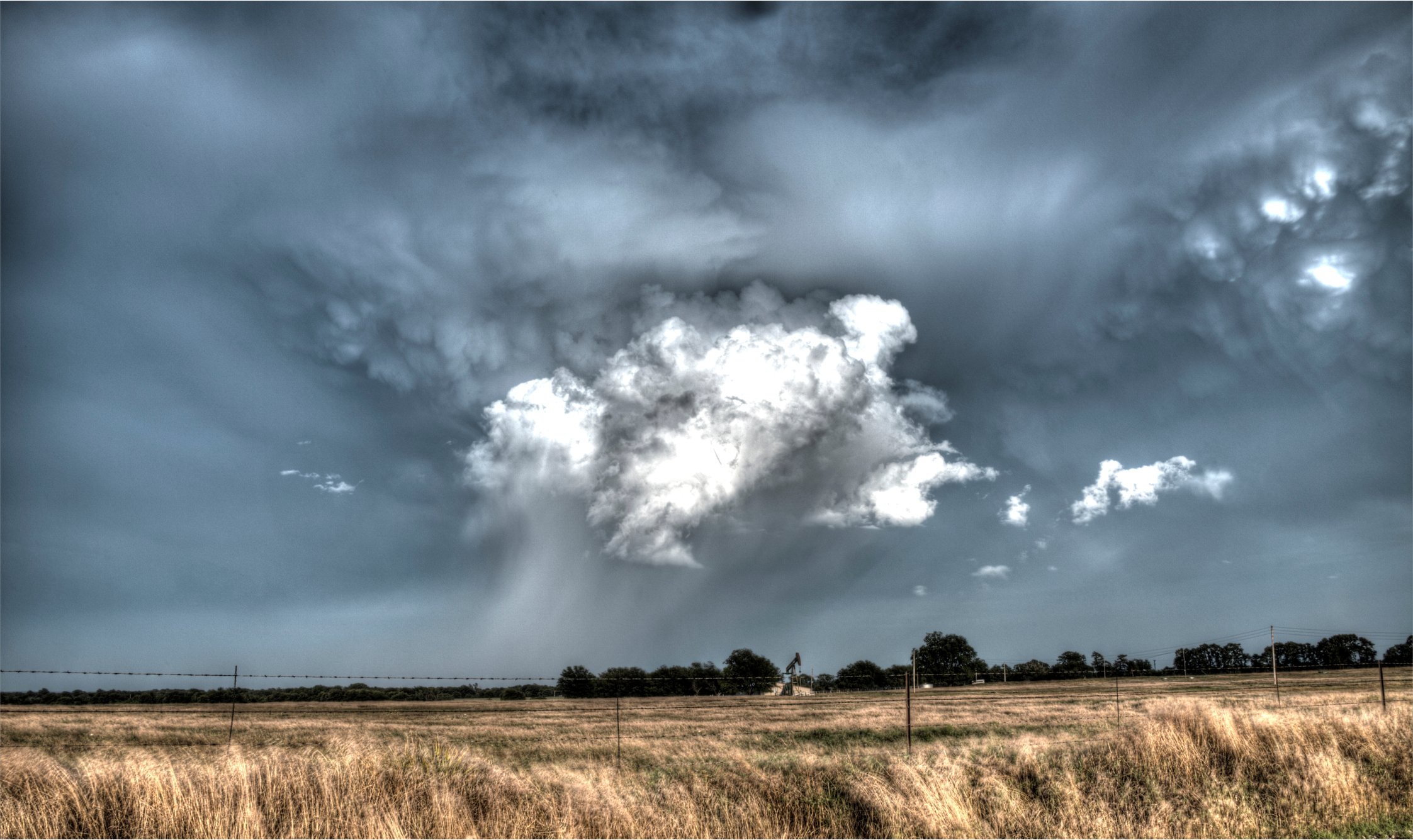 Storm clouds surround an oil pump. 
