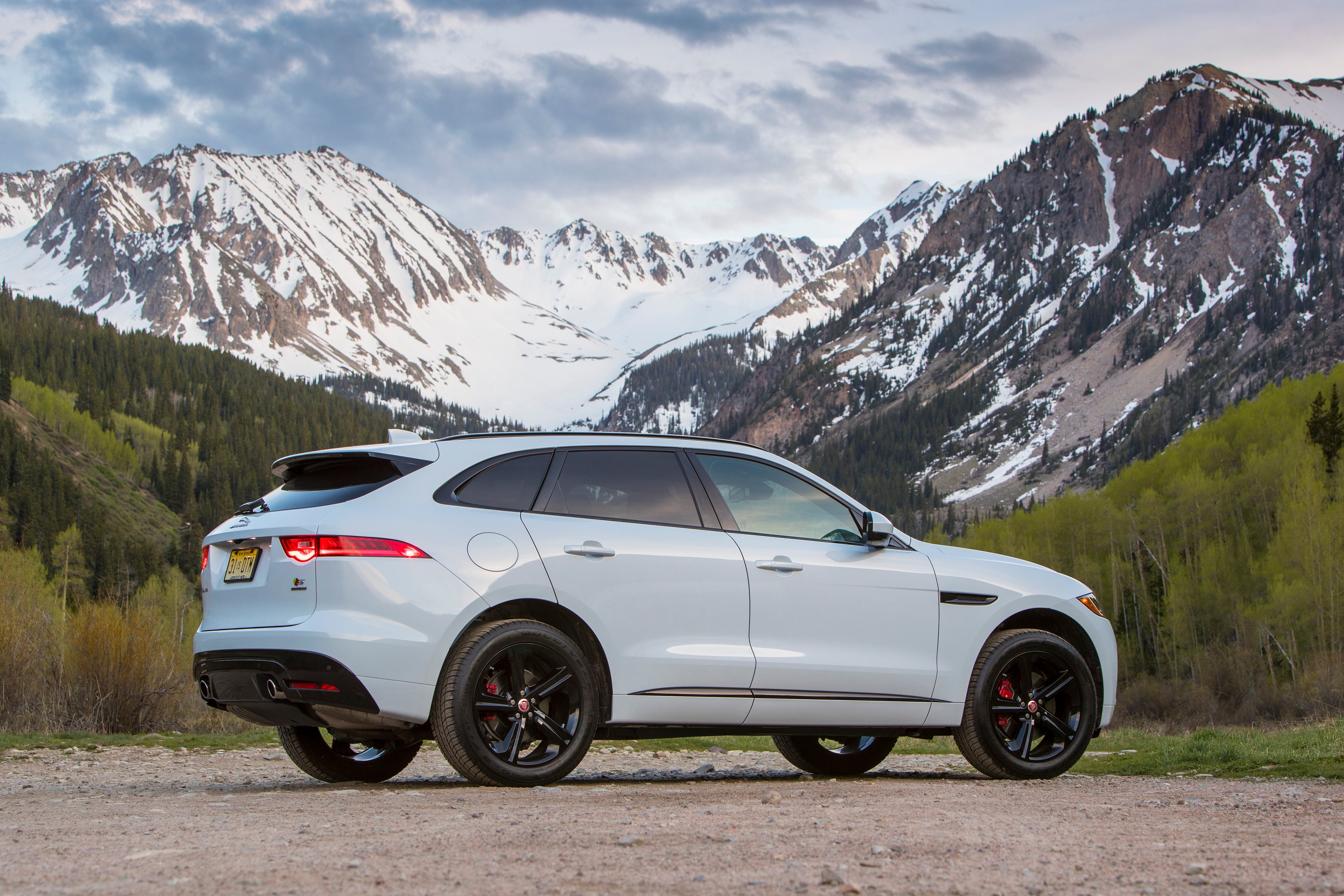 A white Jaguar F-PACE SUV with mountains in the background. 