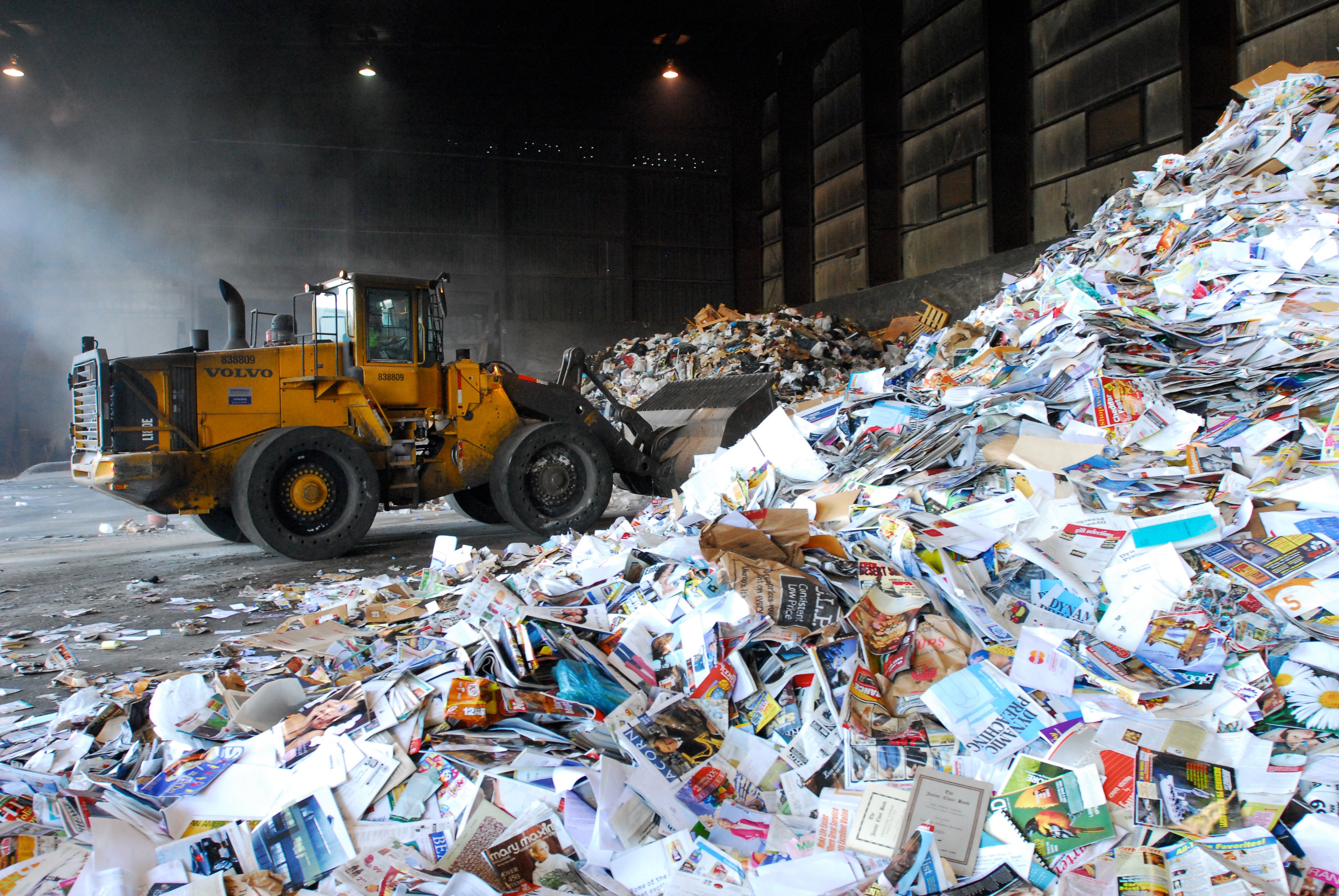 A bulldozer scoops trash from a pile at a Waste Management recycling facility.