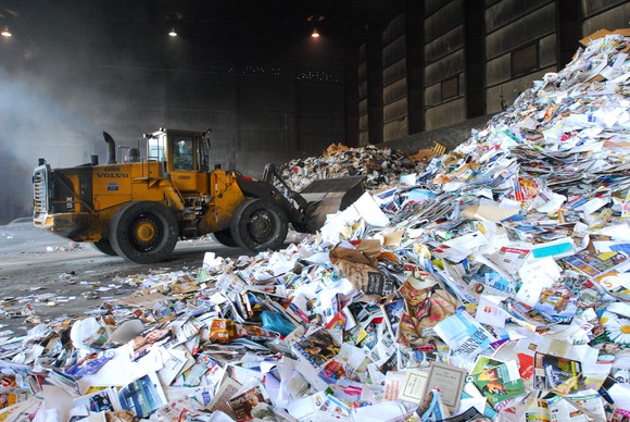 A bulldozer scoops trash from a pile at a Waste Management recycling facility.