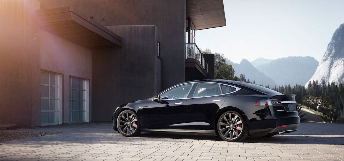 Picture a Tesla Model S sedan parked in the driveway of a house.