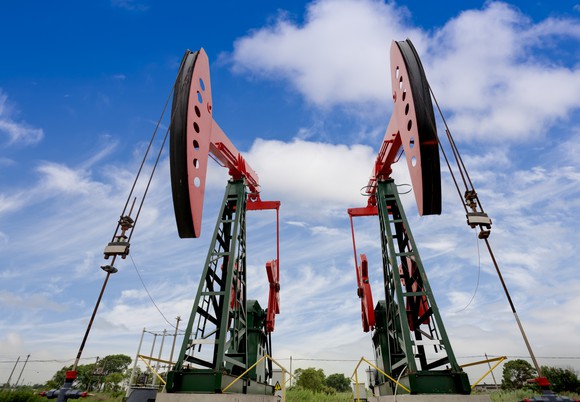 Two oil wells against a warm blue sky.