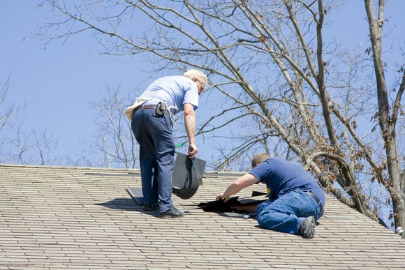 Workers repairing a house's roof