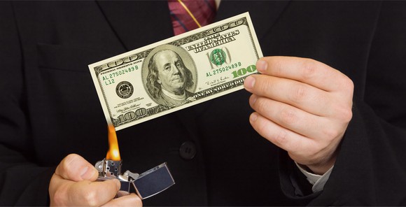 A man burning a hundred dollar bill.