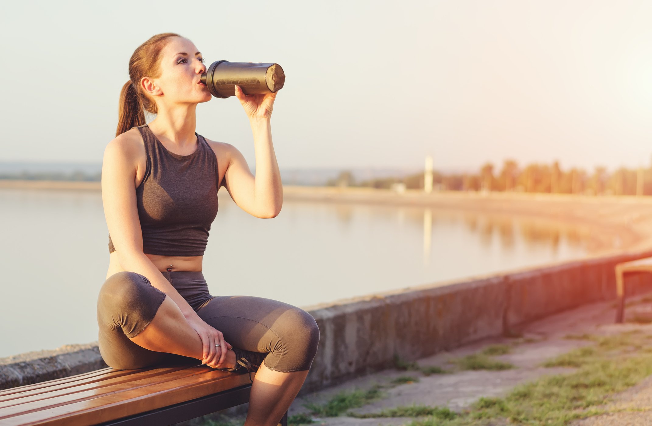 A women drinks a protein shake during a run.
