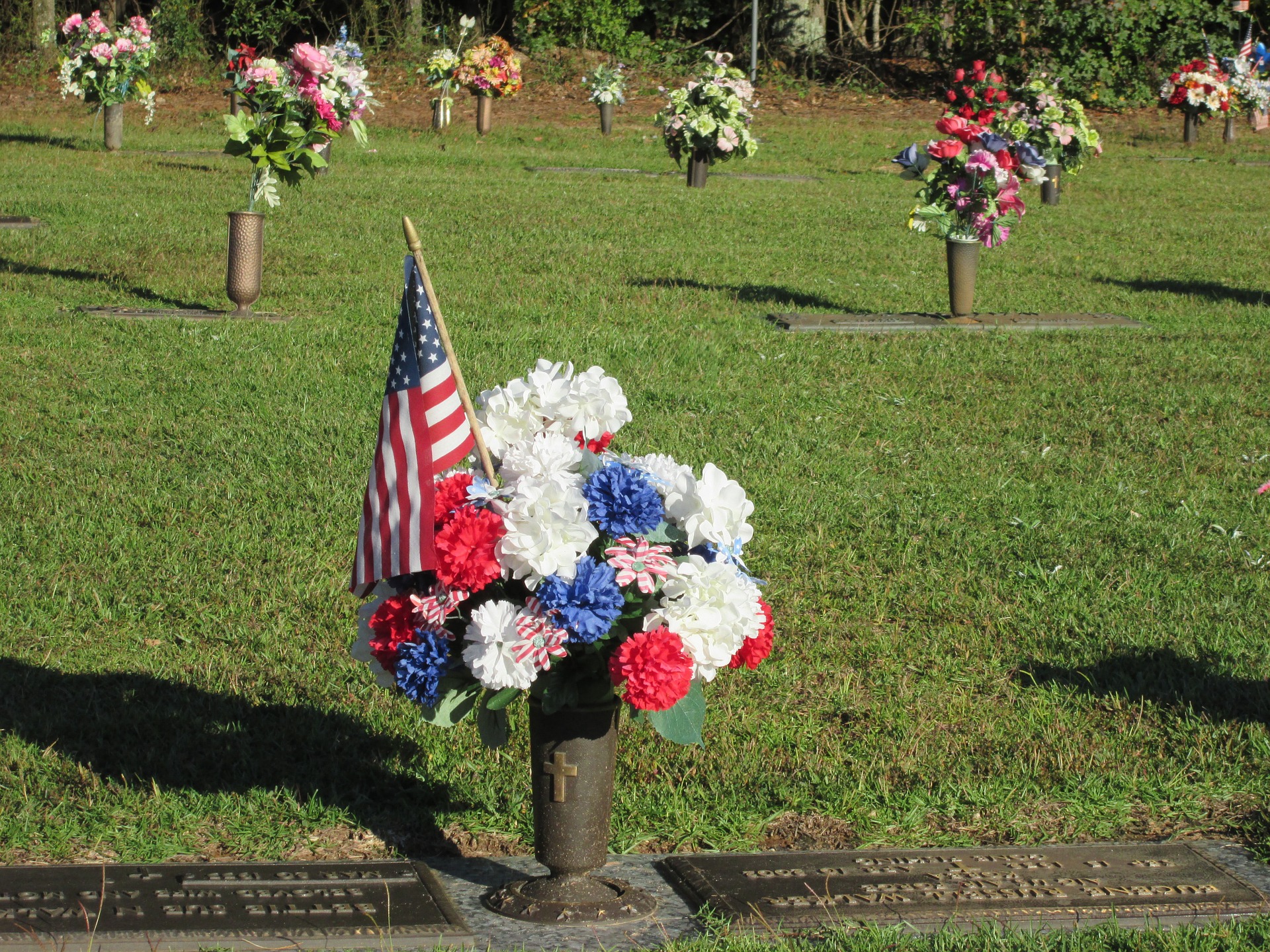 A cemetery with flowers and an American flag on gravestones.