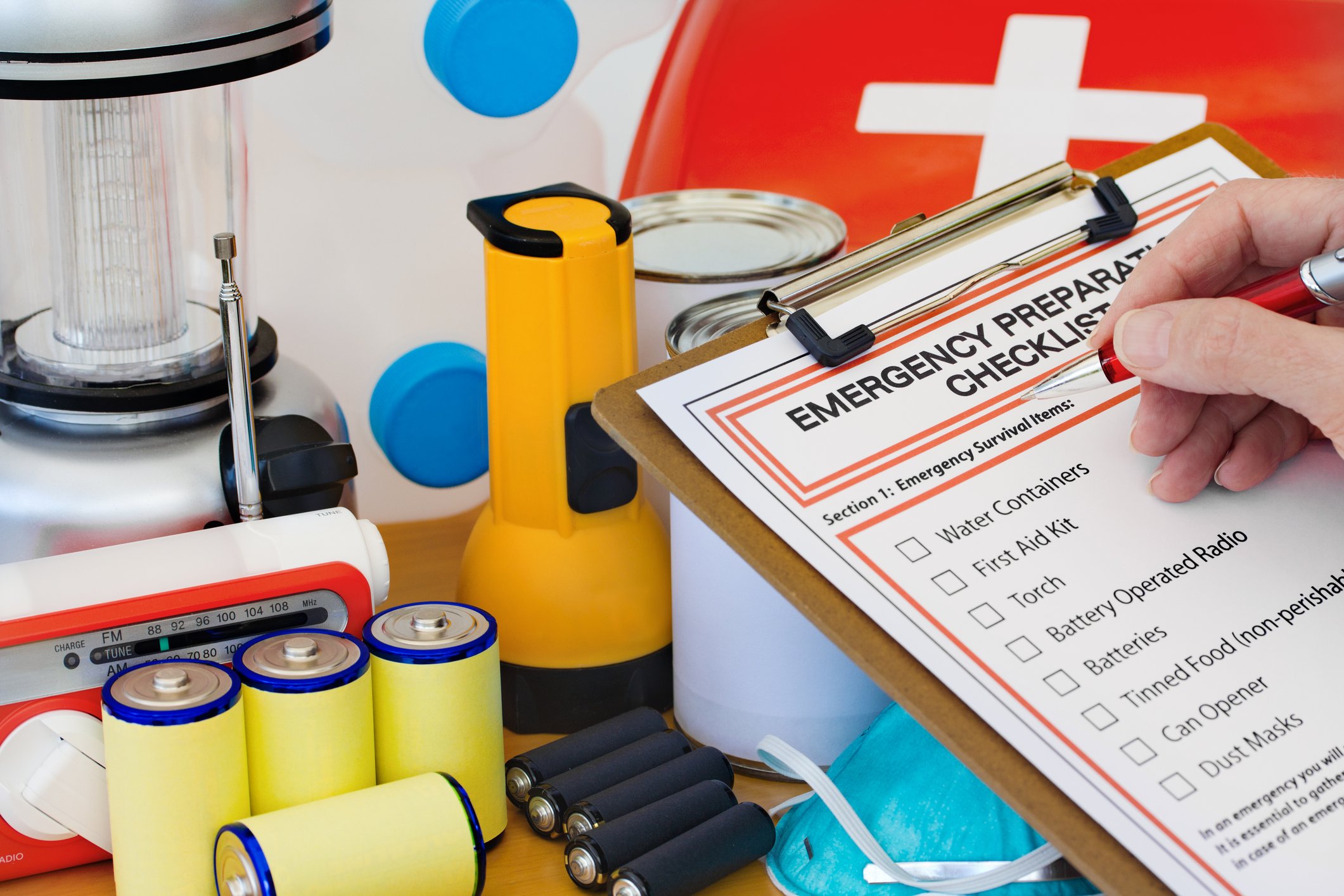 A person fills out an emergency checklist while looking at supplies.