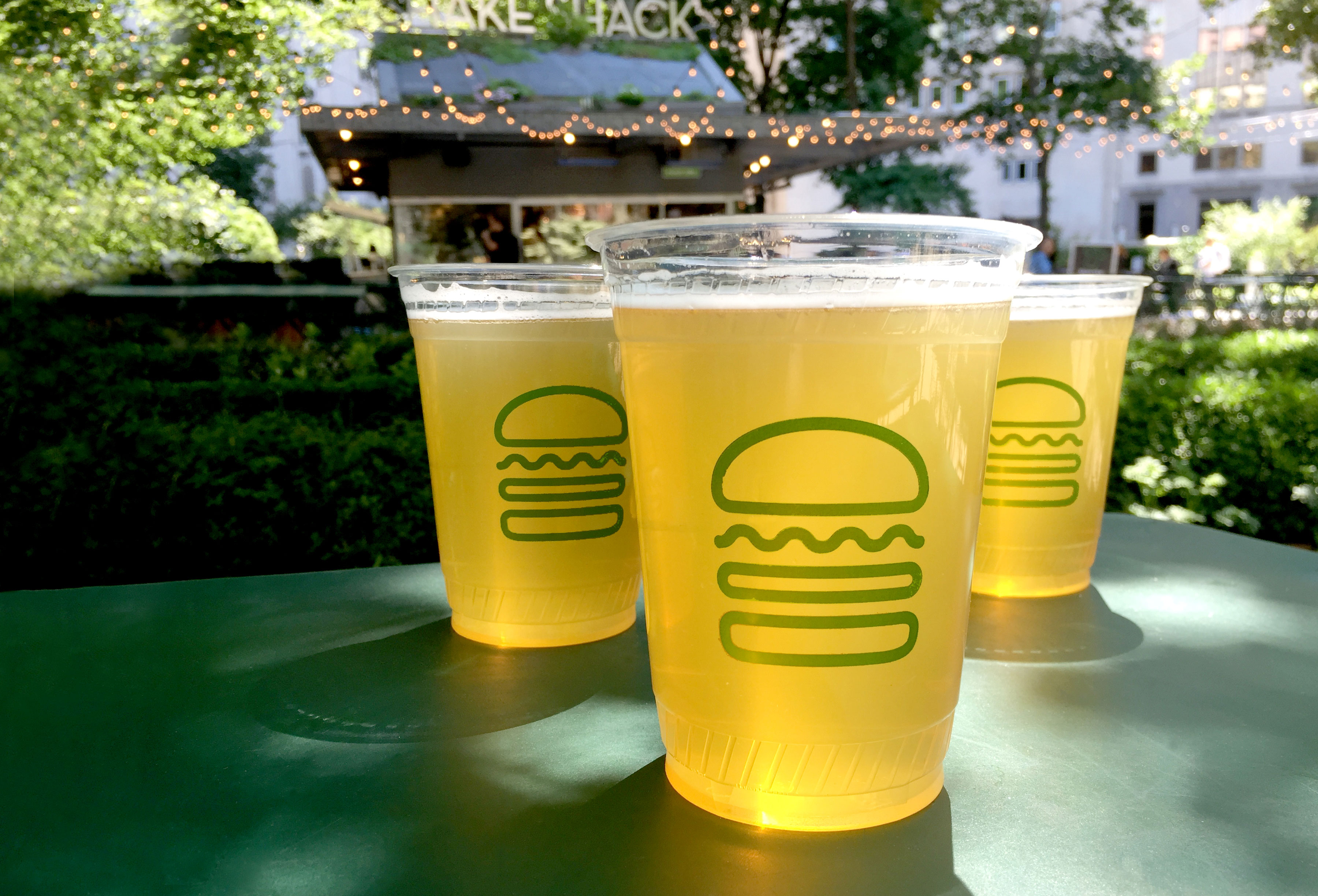 Drinks with the Shake Shack logo in front of a restaurant.