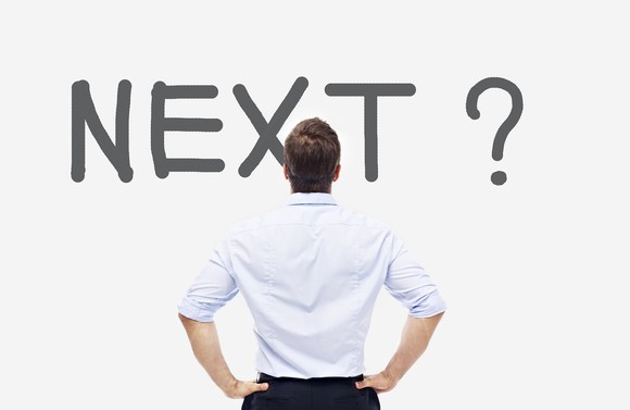 Man standing in front of a sign which reads "next."