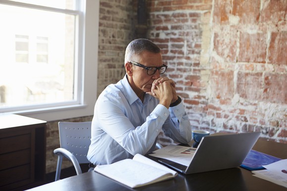 A middle-aged man looking concerned at his desk.