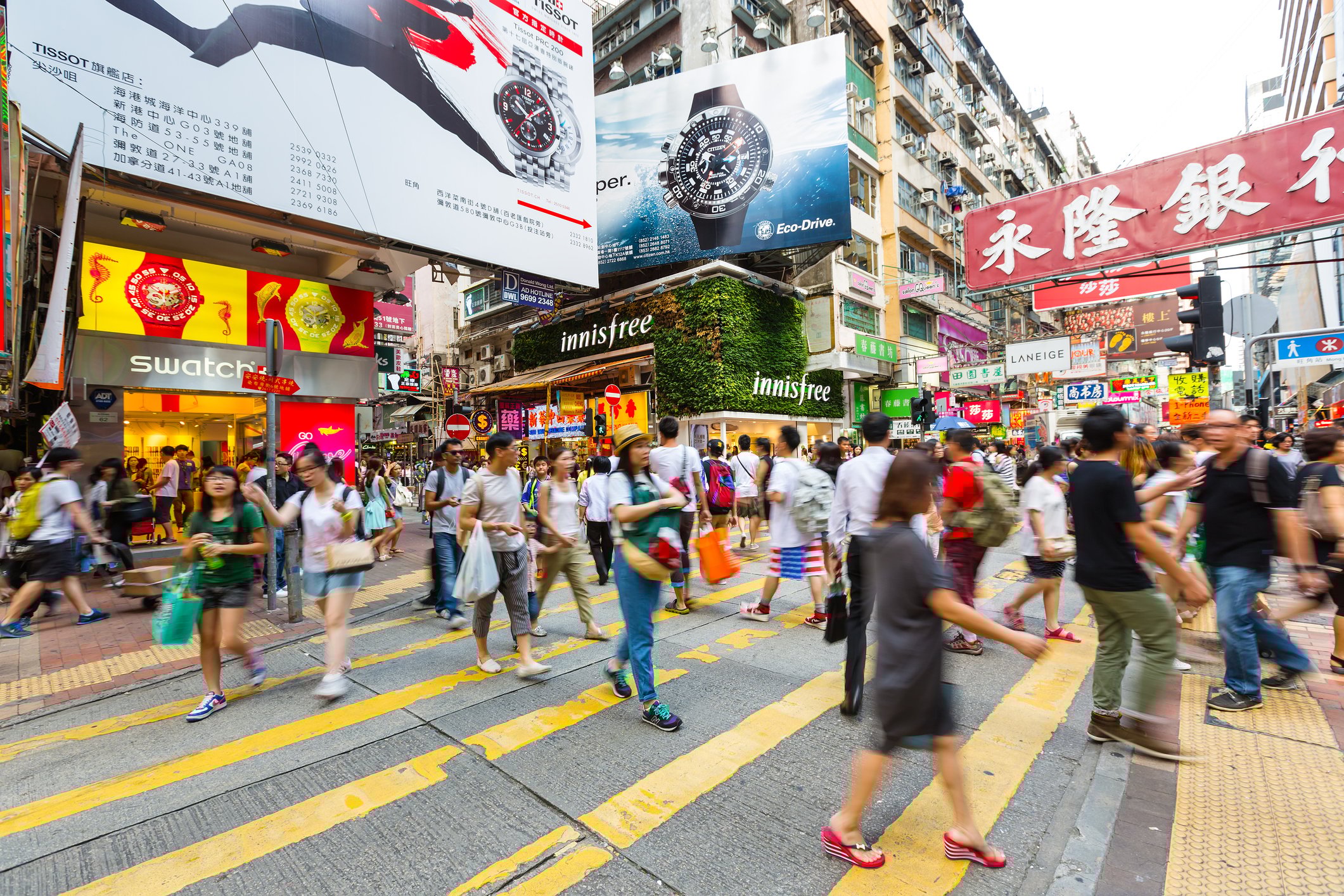 Pedestrians walking on a busy Hong Kong street.