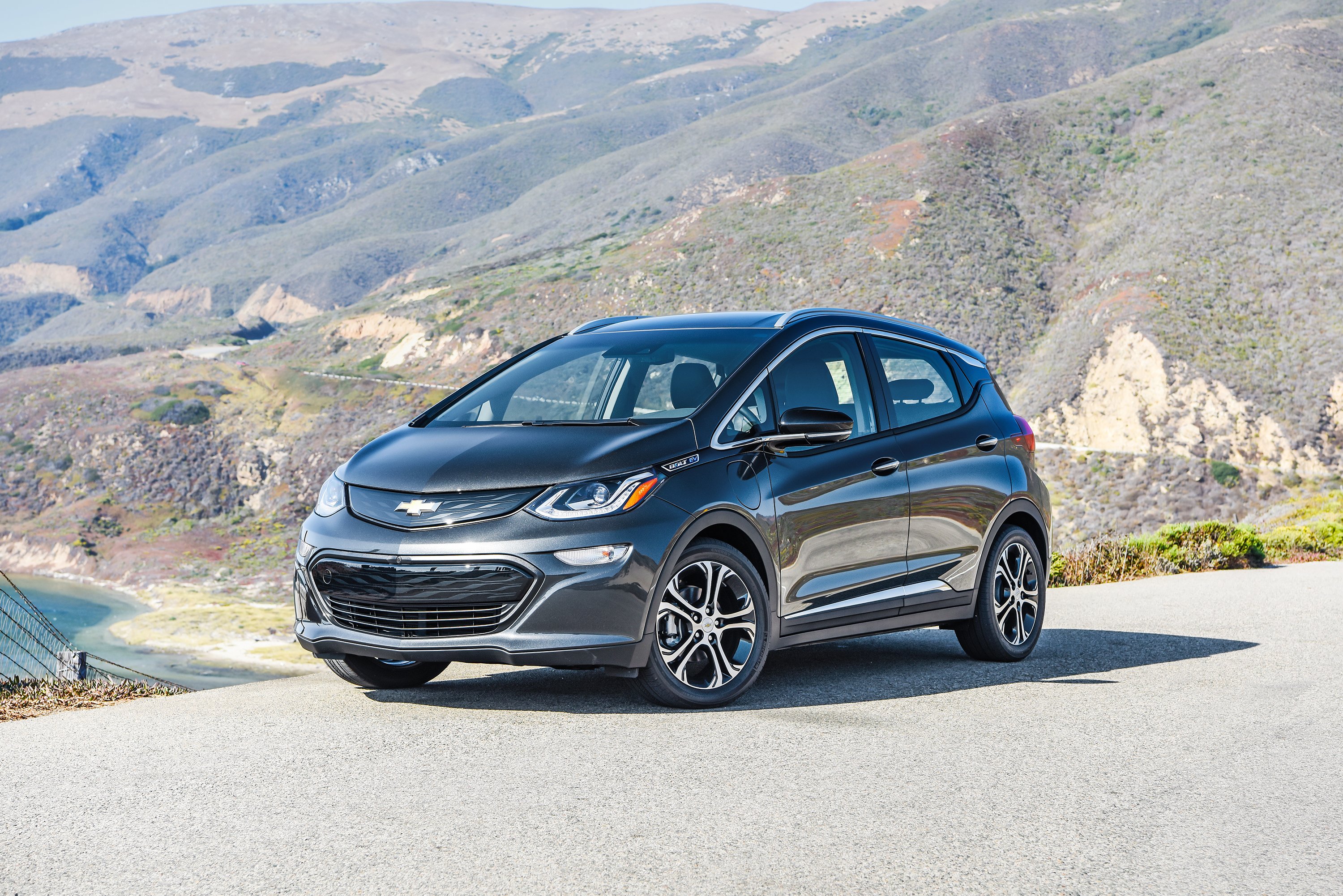 A black Chevy Bolt with mountains in the background.