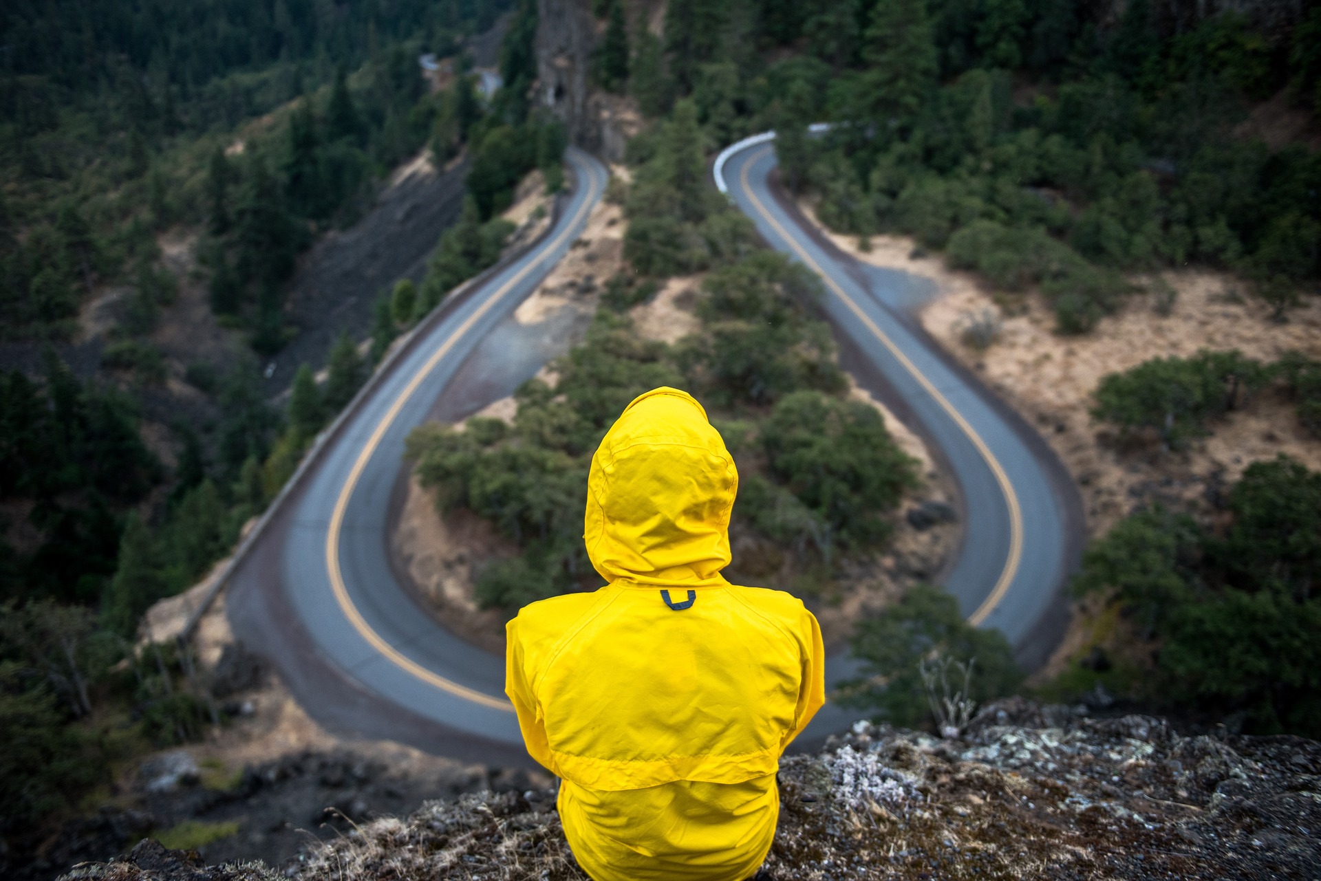 Figure wearing a raincoat starting at winding road