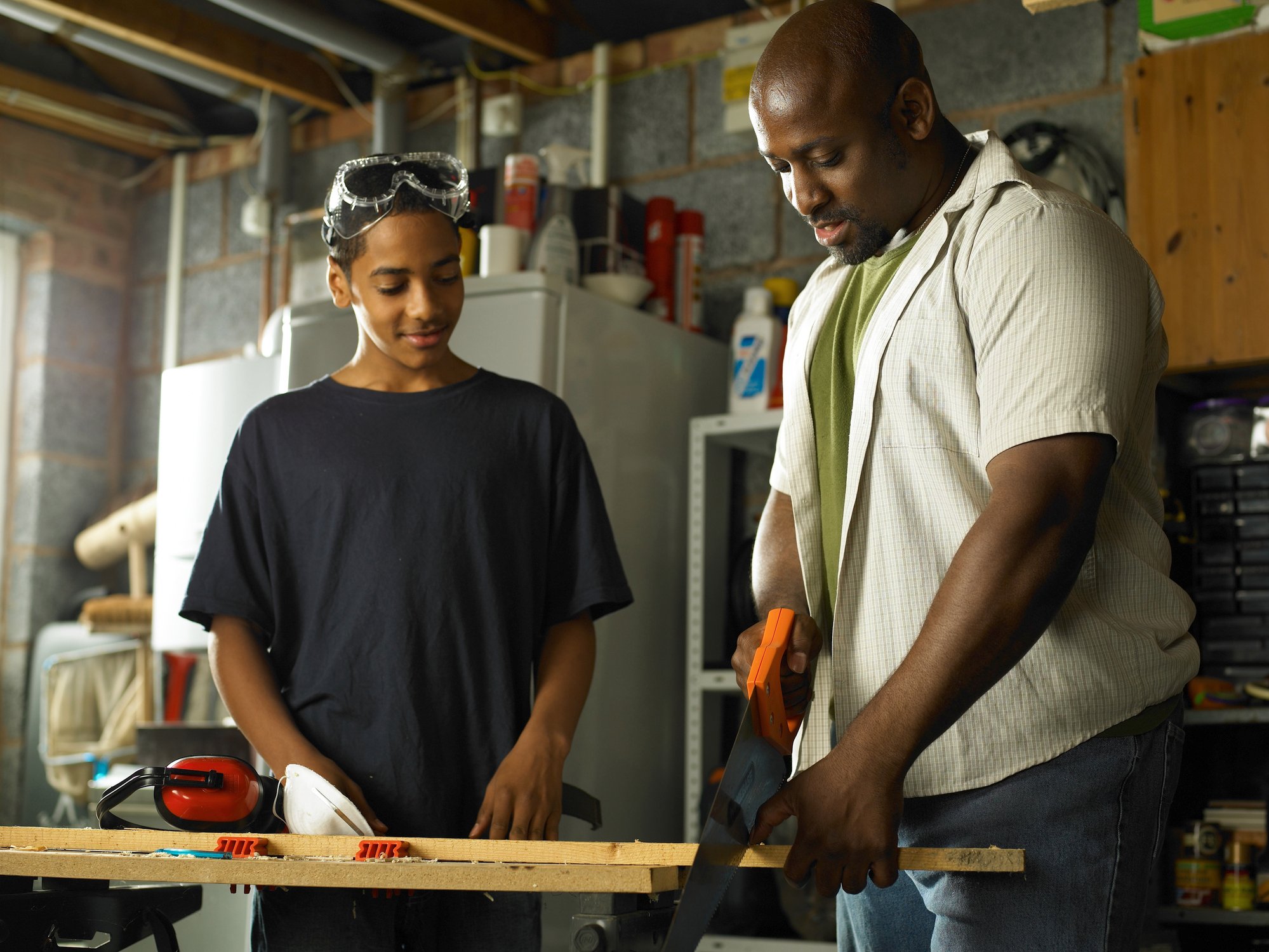 Father teaching his teenage son about carpentry. 
