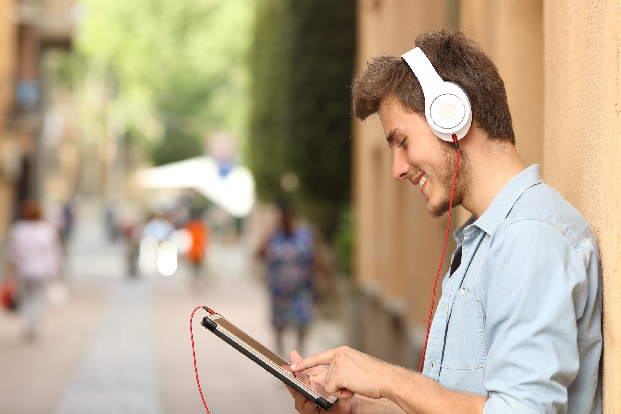 Young man watching his tablet with headphones on.