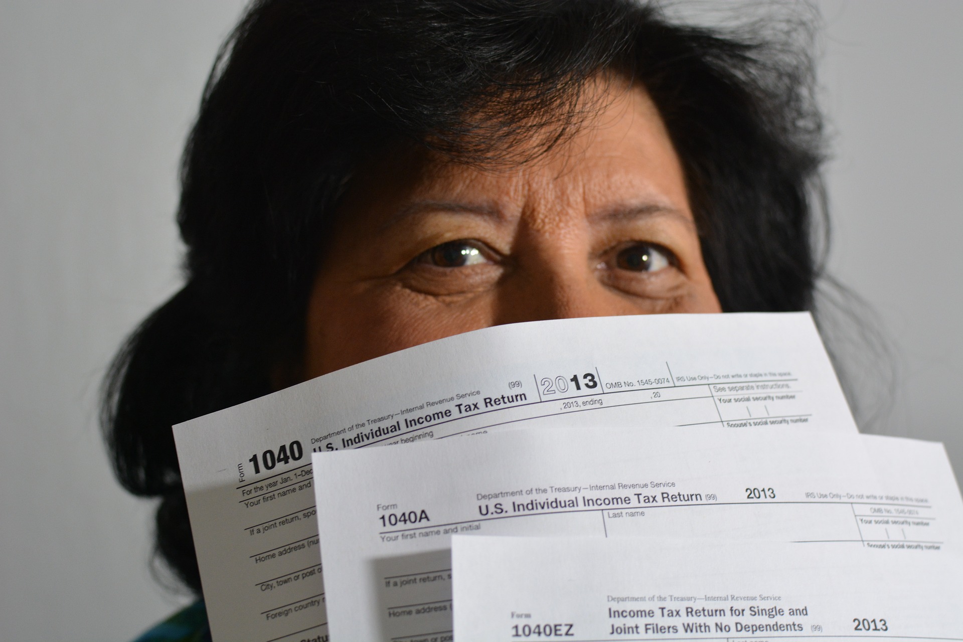 Woman holding tax returns partially concealing her face.