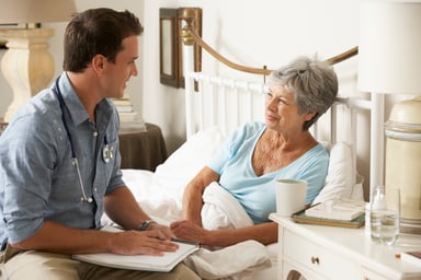Doctor talking with senior patient in bed