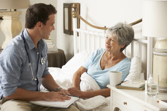 Doctor talking with senior patient in bed