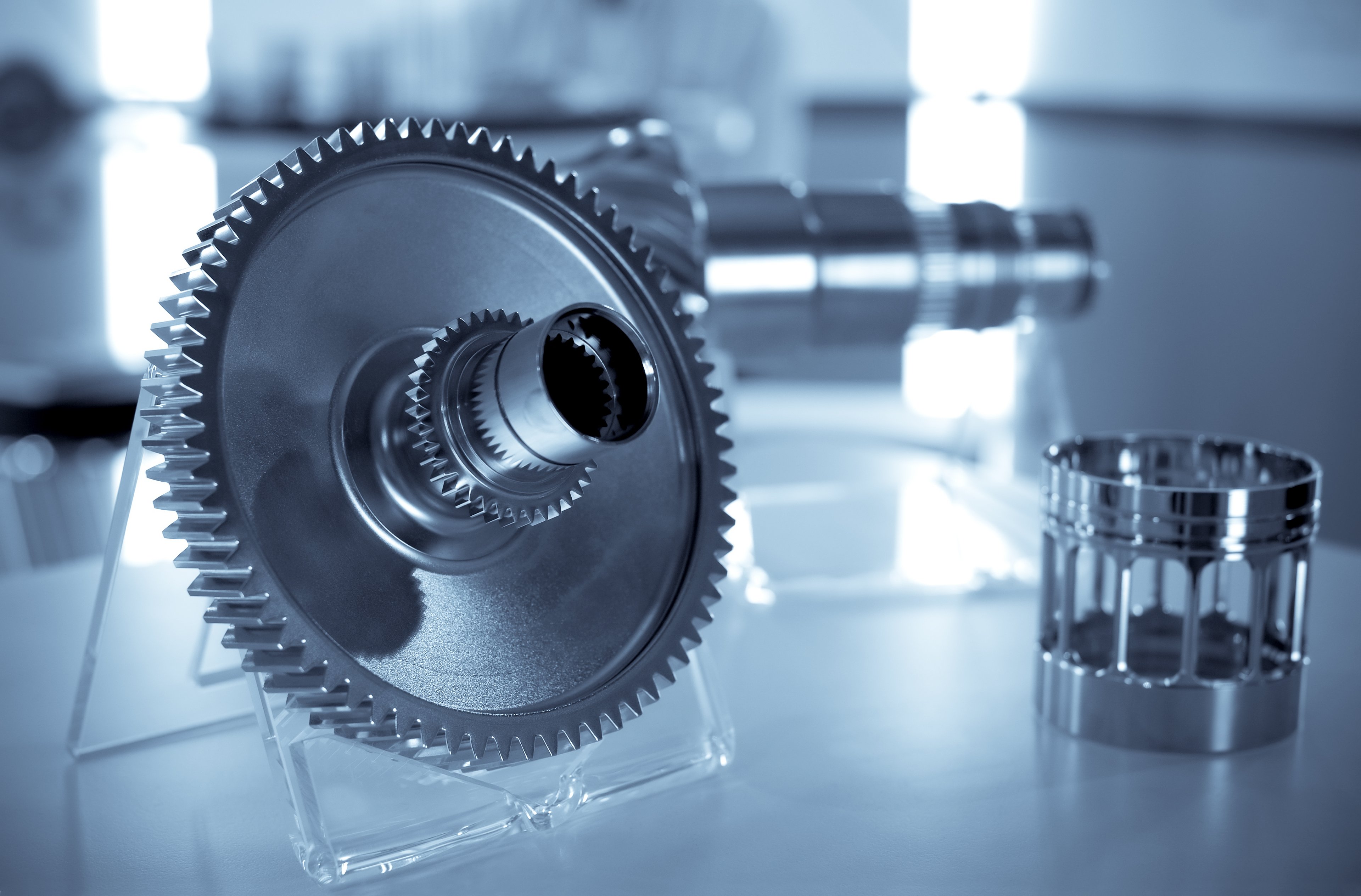 Image of a precision gear and other parts in the background. 