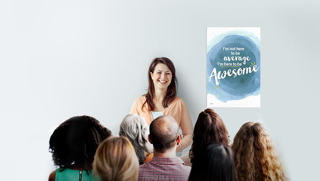 A smiling woman speaking to a group of Weight Watchers meeting participants in front of a sign that reads "I'm not here to be average, I'm here to be awesome."
